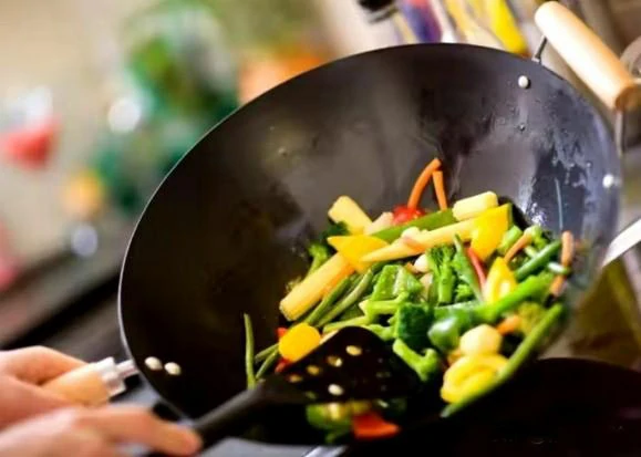 Why shouldn't you rinse an iron wok with water right after cooking?